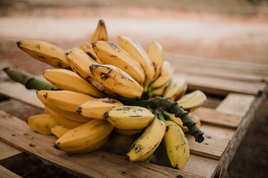 Close-up of ripe bananas on a wooden pallet outdoors in natural light.