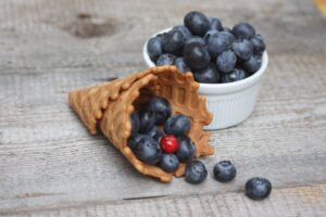 Juicy blueberries in a waffle cone on a rustic wooden table. Perfect for healthy eating themes.