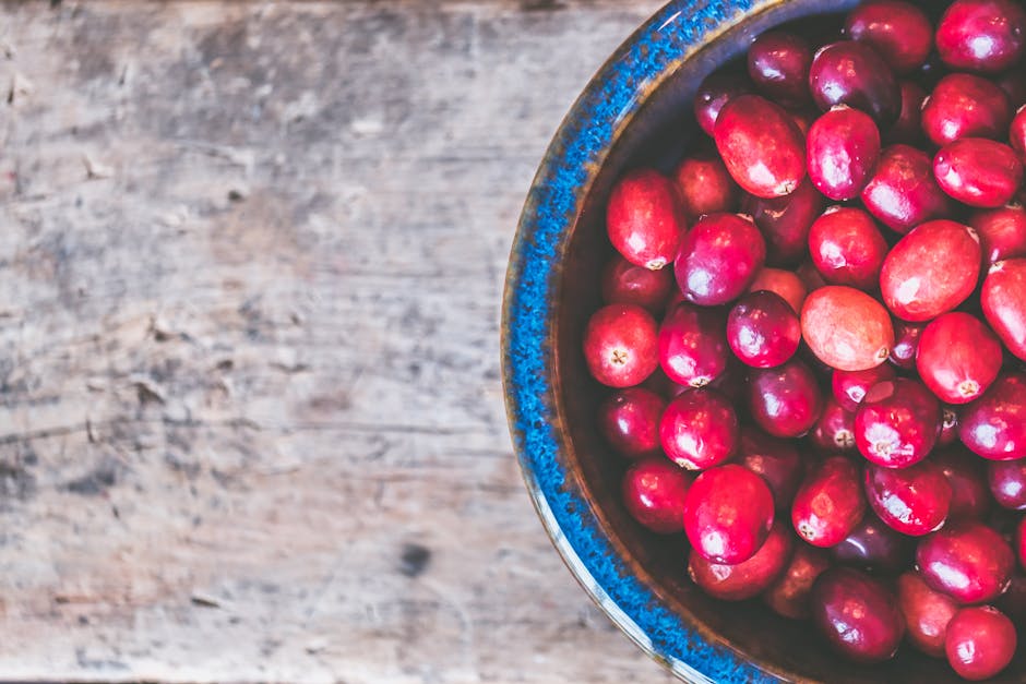 Colorful fresh cranberries in a textured blue bowl on a wooden tabletop creating a rustic and healthy food theme.